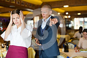 Angry man client of restaurant yelling at young waitress