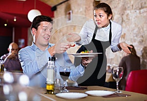 Angry man complaining to apologetic waitress about food in restaurant