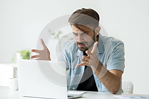 Angry man disagree with fake online news looking at laptop