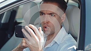 Angry Man Driver Using Smartphone while sitting in a car. Businessman is angry with the message that he read smartphone.