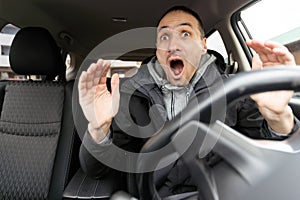 Angry man driving a car. Male driver gesturing and shouting behind the wheel of the car.