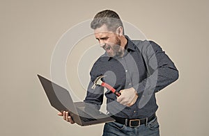 Angry man hit laptop computer with hammer grey background, crash