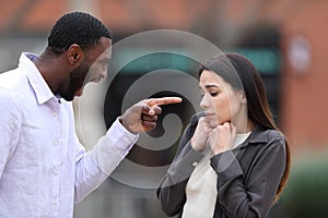 Angry man scolding and accusing to a scared woman