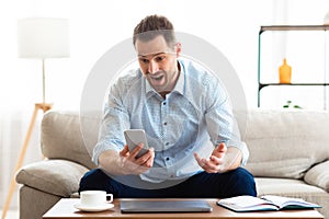 Angry man screaming at mobile phone at home