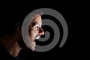 Angry man shouting out loud isolated on black background