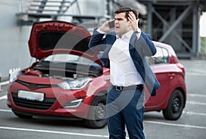 Angry man talking by phone because of broke down car photo