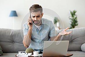 Angry man talking on phone disputing over computer laptop problem