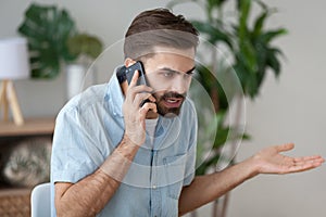 Angry man talking on smartphone solving work problem