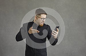 Angry man waves his hand and indignantly shouts at his smartphone after a rough conversation.