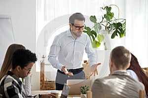 Angry manager boss shouting at group office meeting scolding employees