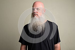 Angry mature bald man with long gray beard thinking