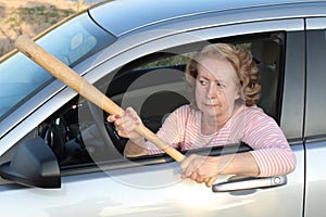 Angry mature female driver holding baseball bat