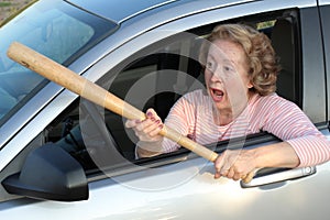 Angry mature female driver holding baseball bat