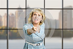 Angry mature woman pointing forward.