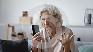 Angry senior woman frustrated by smartphone problems photo