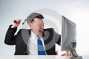 Angry men holding hammer over PC monitor