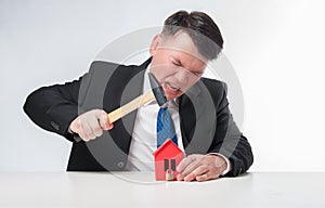 Angry men holding hammer over red paper house