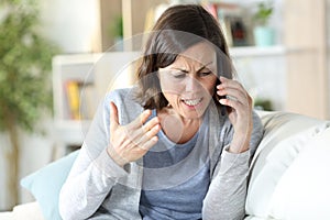 Angry middle age woman arguing calling on phone at home