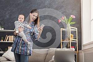Angry mother holding baby while using phone