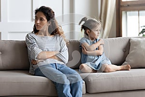 Angry mother and little daughter ignoring each other after quarrel