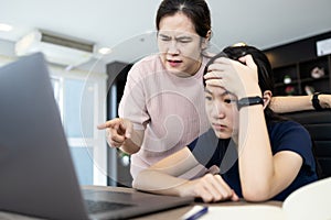 Angry mother scolding her daughter about an education on computer,stressed student suffers from displeasure of female tutor or photo