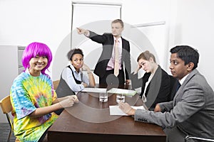 Angry multiethnic businesspeople with colleague in pink wig at meeting