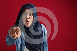 Angry muslim woman wearing hijab looking at camera with threatening intimidating gesture, mad boss pointing at you
