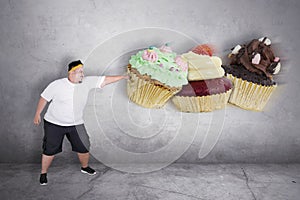 Angry obese man punching cupcakes