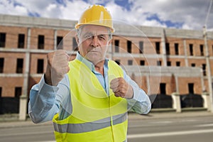 Angry old builder man showing fists as aggressive gesture