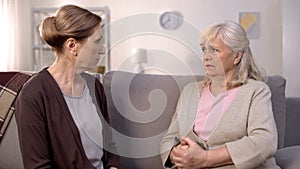 Angry old women looking each other sitting in living room, communication problem