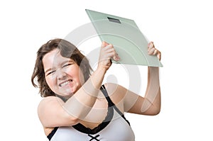 Angry overweight woman is frustrated from her weight. She is throwing scales. Isolated on white.