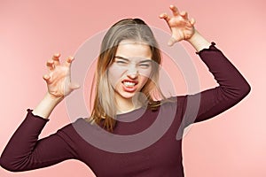 Angry, playful and scares woman is teaseing on the pink studio background and looking at camera