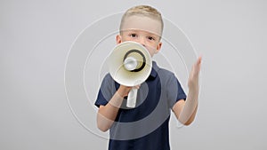 Angry preschooler boy in blue t-shirt yells using white megaphone in studio