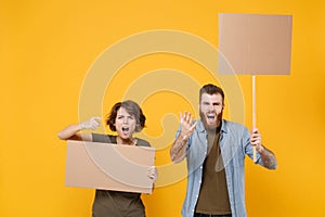 Angry protesting two people guy girl hold protest signs broadsheet blank placard on stick pointing finger on camera