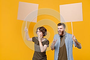 Angry protesting young two people guy girl hold protest signs broadsheet blank placard on stick screaming isolated on