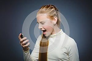 Angry redhead girl with cell phone. isolated on gray