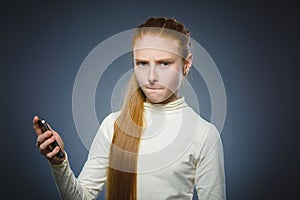 Angry redhead girl with cell phone. isolated on gray