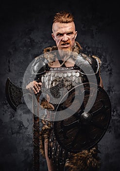 Angry redhead viking warrior posing against dark background