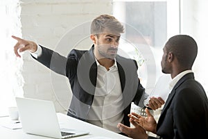 Rude white partner telling black businessman get out his office photo