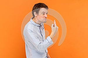 Angry rude man standing looking away with aggression, showing middle finger, fighting with someone.