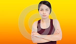 Angry sad asian girl with crossed arms on orange background - Portrait of offended woman with arms crossed looking at camera