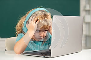 Angry sad child using laptop computer, kid boy studying through online e-learning. Little funny system administrator.