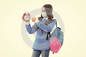 Angry school child in face mask punch alarm clock during COVID-19 disease pandemic, ultimatum photo