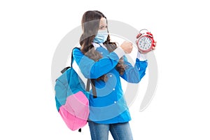 Angry school child in face mask punch alarm clock during COVID-19 disease pandemic, ultimatum photo