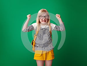 Angry school girl with backpack isolated on green background