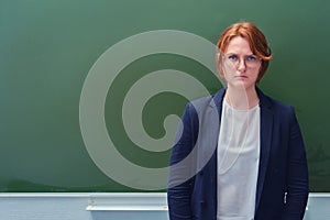 An angry schoolteacher stands at the blackboard with a sad face, copy space