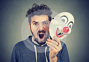 Angry screaming man holding a clown mask