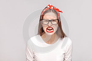 angry screaming portrait of anger crazy bossy emotional young woman in white t-shirt with freckles, black glasses, red lips and h