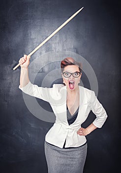 Angry screaming teacher with pointer on blackboard background