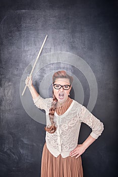 Angry screaming teacher with pointer on blackboard background